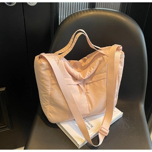 Detail of light pink quilted nylon tote bag with adjustable strap on a chair