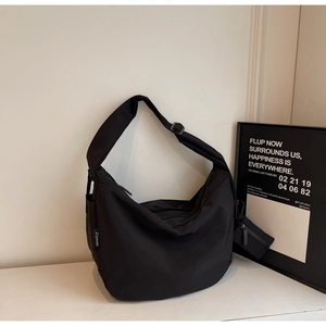 Macro shot of black canvas dumpling bag with adjustable strap and a mini round coin purse