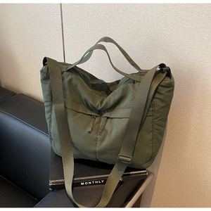 Detail of army green nylon tote bag with wide adjustable strap and front zipper pocket