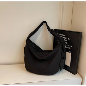 Close-up of black nylon crescent bag with adjustable wide strap and L-youse label detail