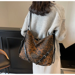 Detail of large leopard print tote bag with black leather straps and brand patch