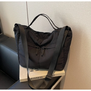 Detail of black nylon tote bag with dual front zippers and adjustable shoulder straps