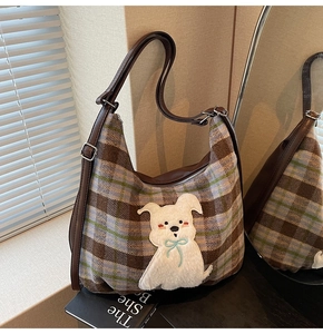 Detail of plaid tote bag featuring fuzzy puppy patch on a book under natural window light