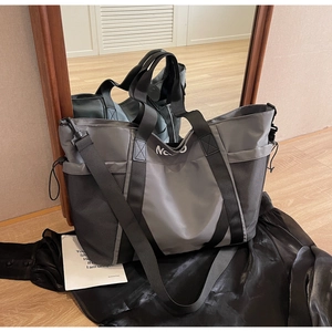 Detalle del bolso tote de nailon gris con bolsillo lateral de malla y correa larga