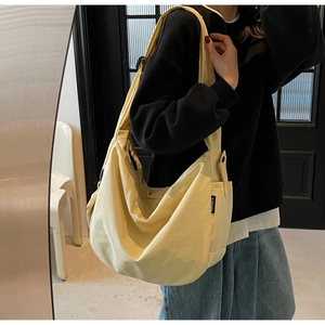 Detail of the pale yellow canvas crescent bag showing texture and adjustable strap