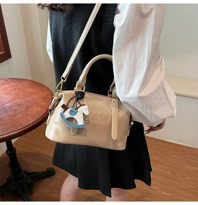 Detail of beige leather handbag featuring gold hardware and a cute horse charm