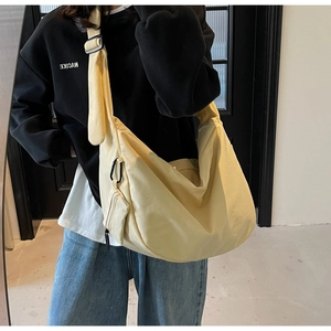 Detail of yellow canvas dumpling bag featuring adjustable strap and a detachable coin purse