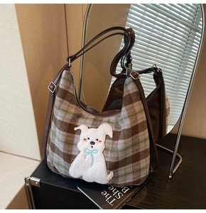 Detail of checkered tote bag featuring a cute plush puppy patch and adjustable leather strap