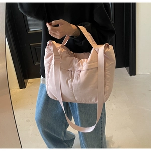 Detail of light pink padded nylon tote bag with adjustable shoulder strap and zip pocket