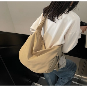 Close-up of beige canvas dumpling bag with a mini pouch and wide shoulder strap