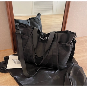 Detalle de un bolso grande de nailon negro con bolsillos de malla y correa ajustable