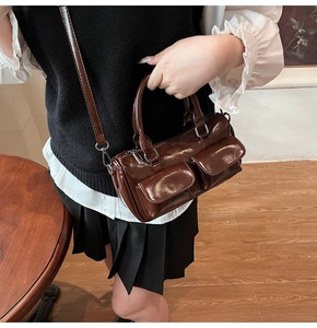 Detail of dark brown glossy PU leather handbag with dual front pockets and silver hardware