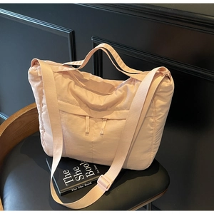 Detail of light pink quilted nylon tote with adjustable strap on a black chair