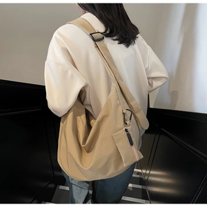 Detail view of khaki canvas crossbody bag with wide adjustable strap and mini pouch