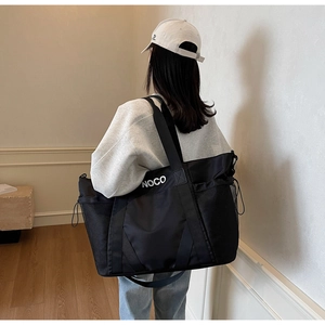 Primer plano de un gran bolso de viaje negro con estampado NOCO y bolsillos de malla