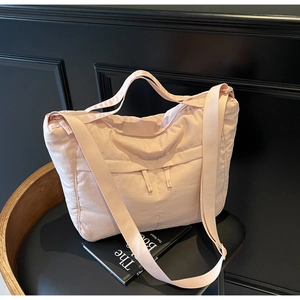 Detail view of pink quilted nylon tote with double zippers and wide shoulder strap