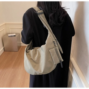 Close-up of khaki green canvas crossbody bag featuring a detachable mini zipper pouch