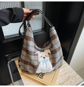 Macro view of vintage plaid hobo bag with cute plush puppy patch and leather strap