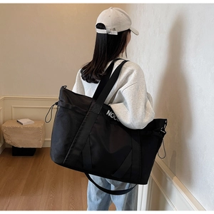 Detalle de bolsa de viaje negra con estampado NOCO y bolsillos de malla en uso real