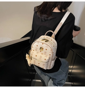 Detail of cream mini backpack with teddy bear prints, golden zippers, and bear charm