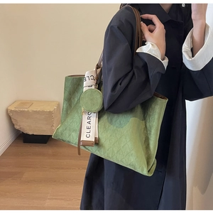 Detail of green suede tote bag with quilted pattern, mini coin purse and ribbon charm