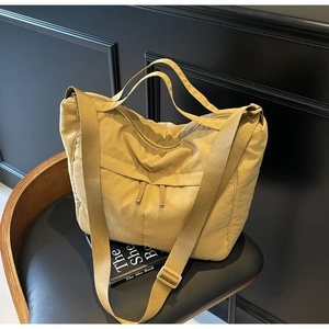 Detail of khaki nylon tote bag featuring dual front zippers and adjustable shoulder strap