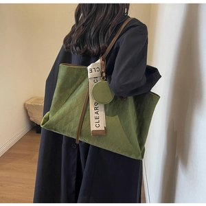 Detail of dark green quilted tote bag with lettered strap and plush velvet texture