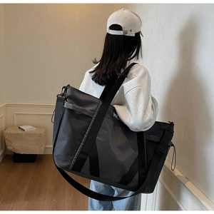Detalle de una gran bolsa de viaje gris y negra con bolsillo de malla en modelo