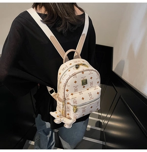 Detail of a chic cream mini backpack with brown bear prints and golden logo badge