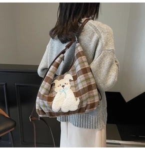 Detail view of large plaid tote bag with plush puppy embroidery and adjustable brown strap