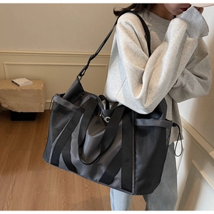 Detalle de bolsa de deporte gris oscuro con bolsillo de malla y correa de hombro ajustable