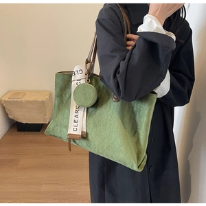 Detail of green quilted tote bag with matte finish and round coin purse hanging detail