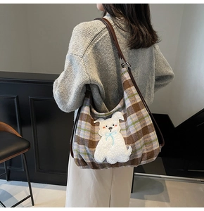 Detail of checkered tote bag with cute cartoon dog patch and brown leather shoulder strap