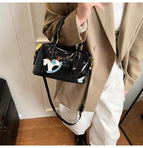 Detail of black patent leather Boston bag with golden hardware and letter embossing