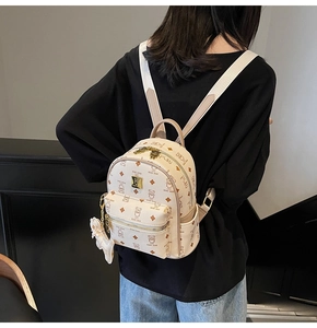 Close-up of beige mini backpack featuring brown teddy bear patterns and a matching charm