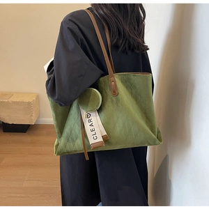 Detail of green suede tote bag featuring diamond quilted texture and round coin purse