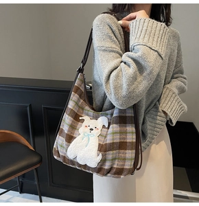 Detail of checkered shoulder bag with 3D plush dog patch and brown leather strap