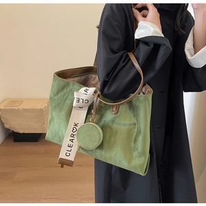 Detail view of olive green quilted tote bag with wide strap and mini round pouch charm