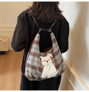 Detail of large check hobo bag with cute plush puppy applique and long leather strap