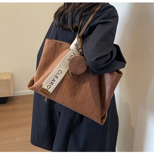 Detail of deep brown tote bag with embossed rhombus pattern and wide fabric shoulder strap