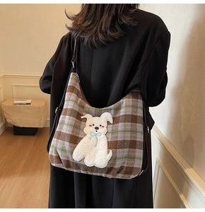 Detail of plaid tote bag featuring a cute plush dog patch and adjustable leather strap