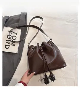 Détails du sac seau en cuir marron foncé avec fermeture à cordon et pompons élégants