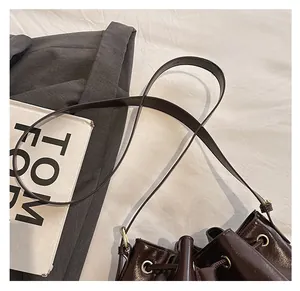 Gros plan du sac seau marron foncé vintage avec cuir brillant et boucles dorées