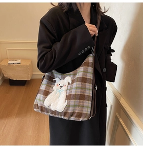 Detail of vintage plaid tote bag featuring a white dog patch and dark brown leather straps