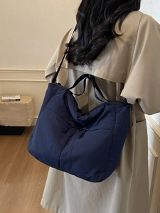 Large capacity navy blue nylon tote bag for women worn with a classic beige coat