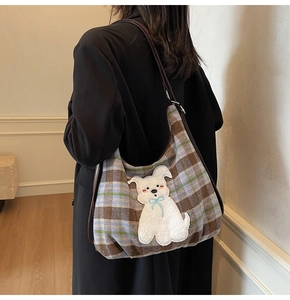 Detail of plaid tote bag with 3D white puppy patch worn by model over black coat