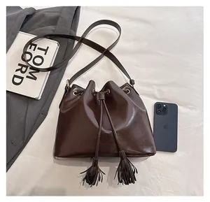 Vue de dessus d'un sac seau marron foncé à cordon et glands sur un fond lifestyle blanc