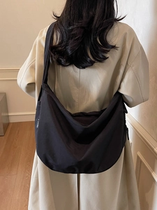 Large black minimalist canvas half-moon crossbody bag shown in a lifestyle street style