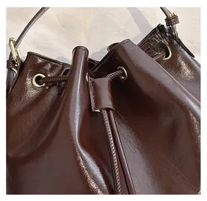 Détail du sac seau en cuir marron foncé brillant avec cordon de serrage et œillets dorés