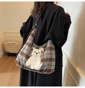 Detail of hobo shoulder bag with plaid fabric texture and cute cartoon puppy patch